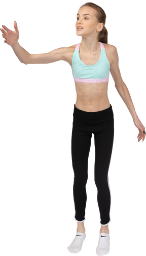Vista frontal de uma adolescente em roupas esportivas levantando a mão enquanto diz algo