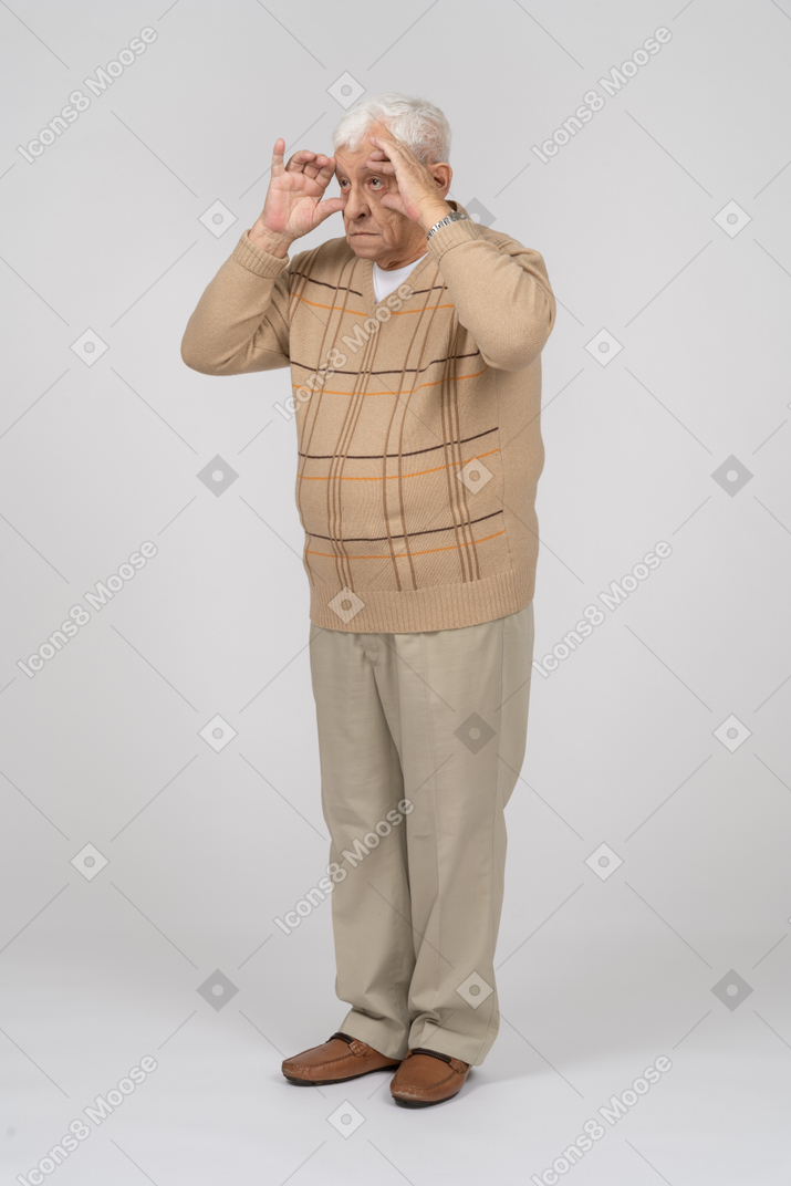 Vista frontale di un uomo anziano in abiti casual che guarda attraverso le dita