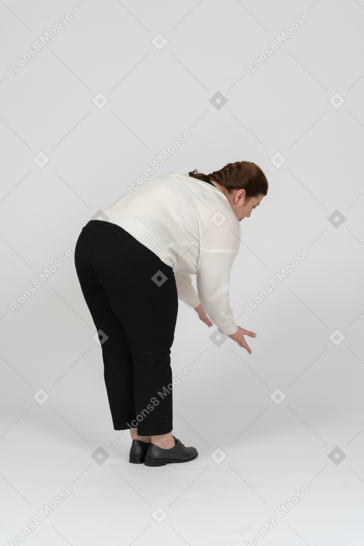 Side view of a plus size woman in casual clothes bending down