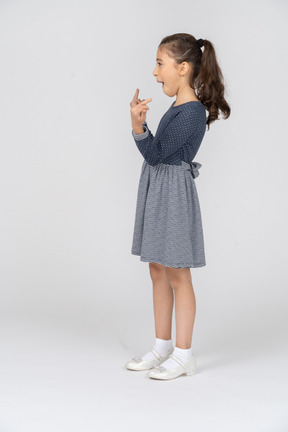 Vista lateral de uma garota mostrando os dedos alegremente