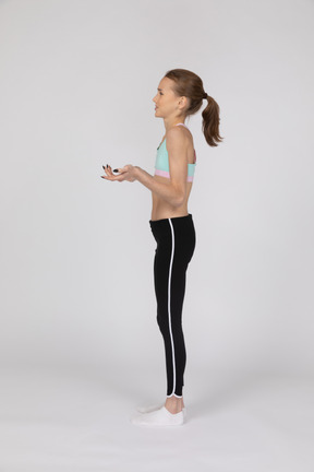 Side view of a displeased teen girl in sportswear raising hands