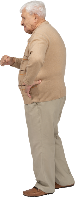 Side view of an angry old man in casual clothes standing with hand on hip
