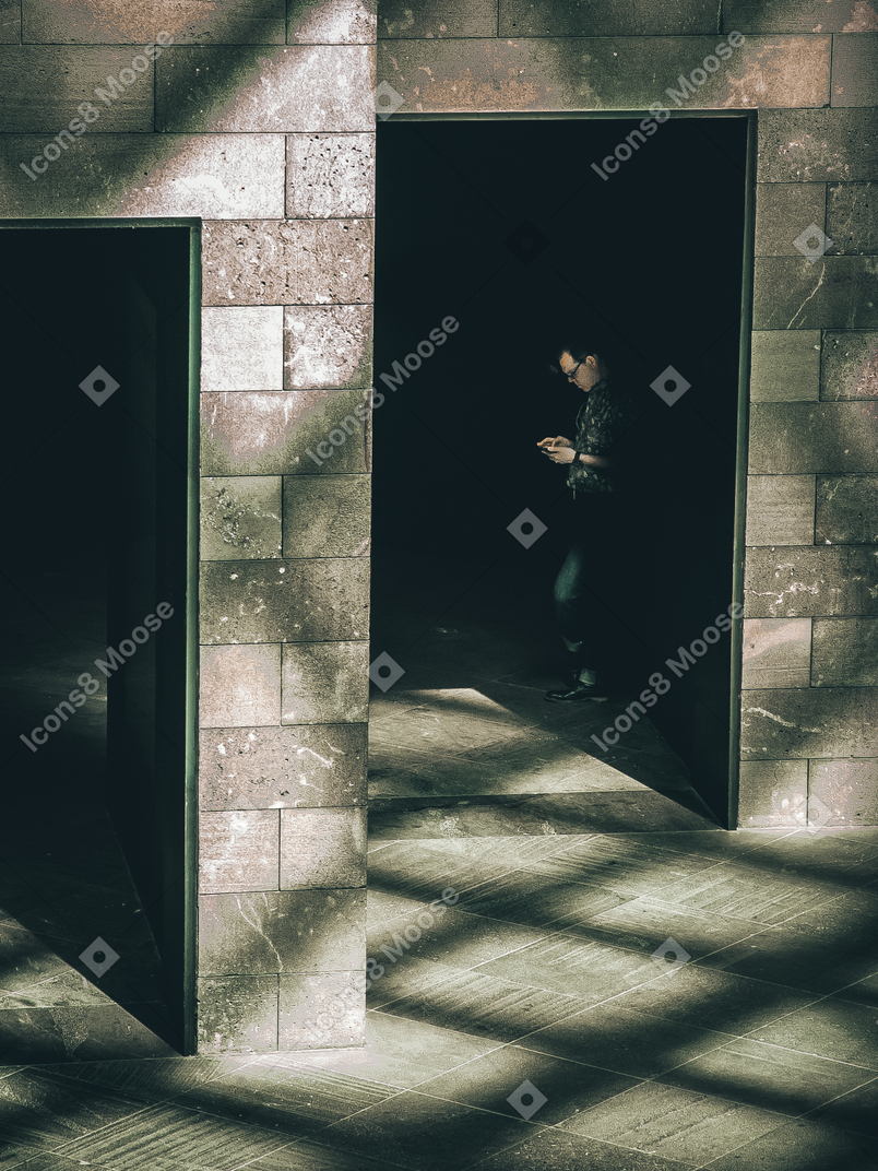 Man standing inside of a building and reading something on phone