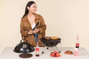 Souriante jeune femme asiatique faisant un barbecue
