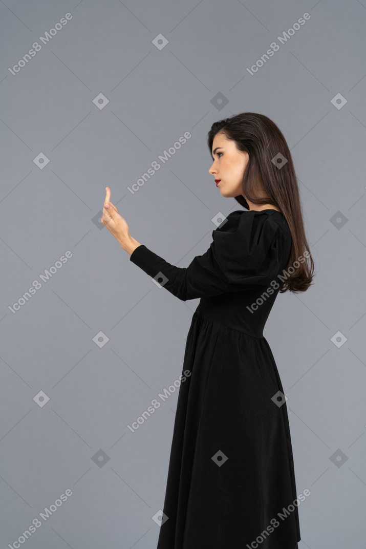 Seitenansicht einer jungen dame im schwarzen kleid mit mittelfinger