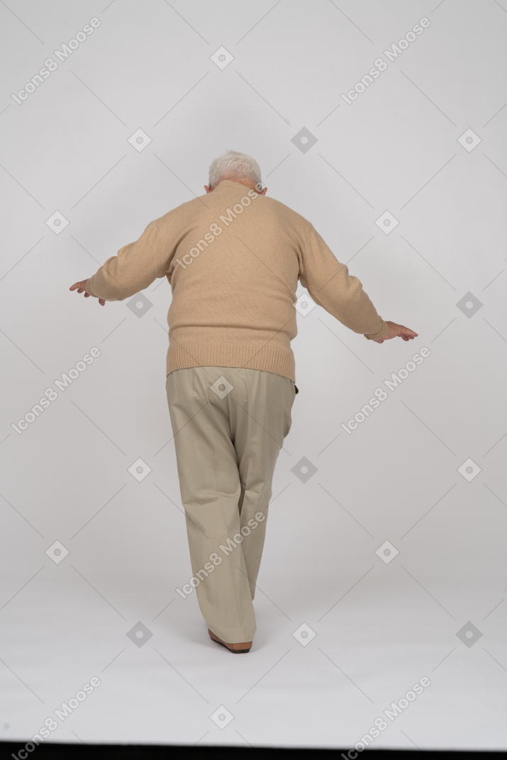 Rear view of an old man in casual clothes walking