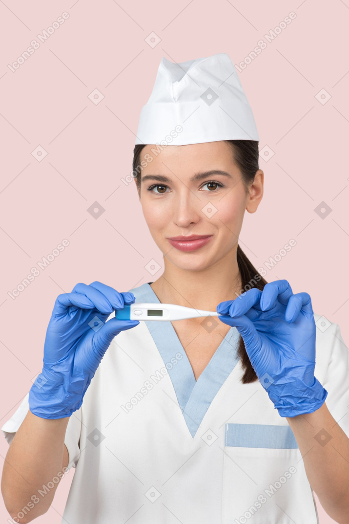 A woman in scrubs holding a thermometer