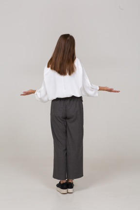 Vista posterior de una señorita en ropa de oficina extendiendo los brazos