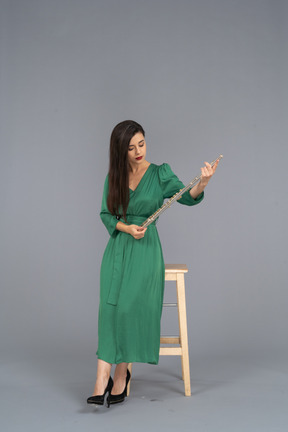 一位年轻的女士，穿着绿色的衣服，坐在椅子上，拿着单簧管的前视图