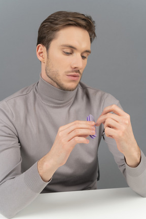 A focused young man using a fingernail file