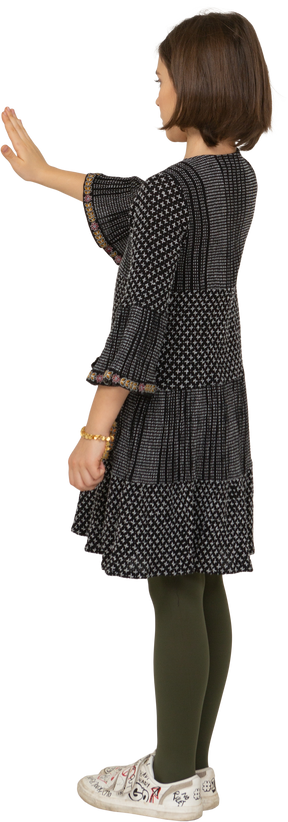 Трехчетвертный вид сзади маленькой девочки в платье, протягивающей руку