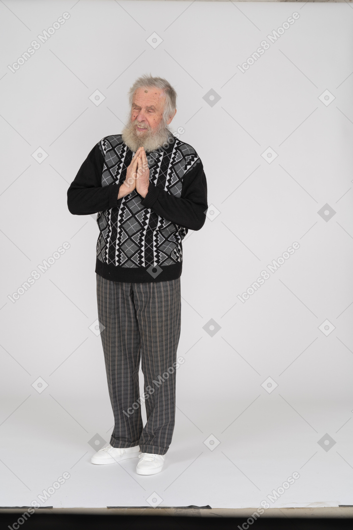 Uomo anziano sorridente in piedi con le mani giunte