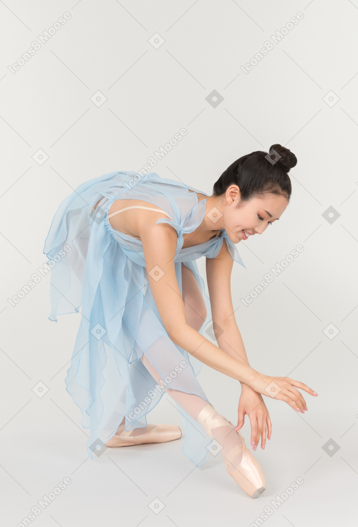 优雅的年轻芭蕾舞女演员弯下腰