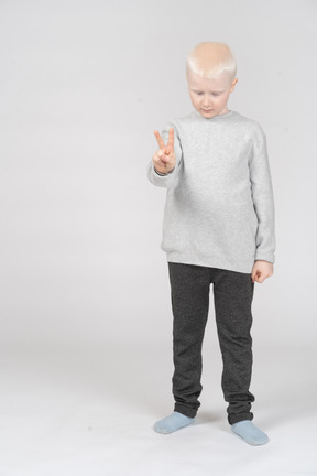 Little boy showing peace sign while looking down