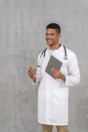 Médico sorridente com tablet conversando com alguém