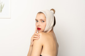 静けさのジェスチャーをする頭の包帯を持つ若い女性