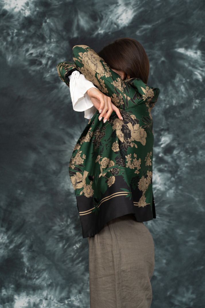 Side portrait of young woman in silk jacket hiding her face