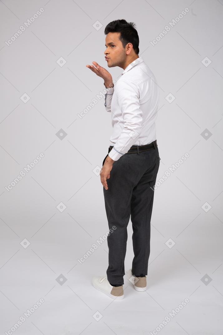 A man in a white shirt and black pants blowing a kiss