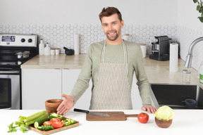 A man standing in a kitchen next to a cutting board