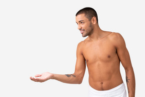 Barechested young male standing in profile with his hand elongated