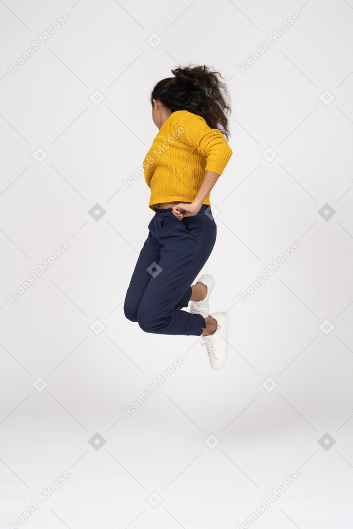 Vue de face d'une fille en vêtements décontractés sautant