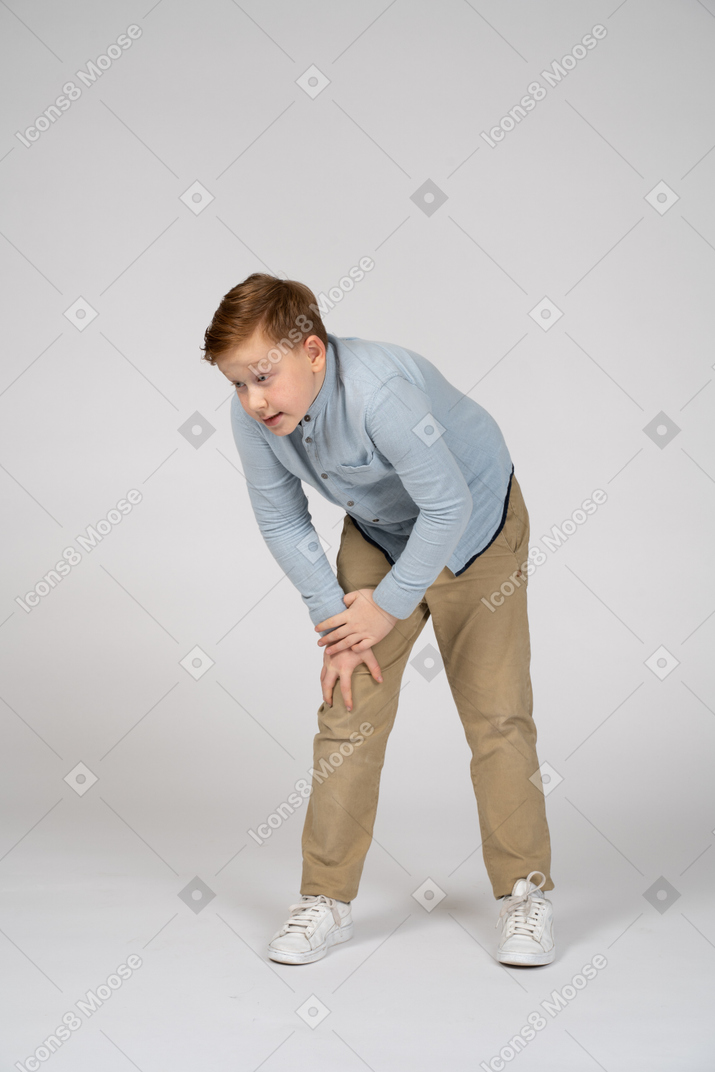一个男孩弯下腰，触摸受伤的膝盖的正面图