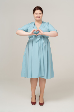 Front view of a woman in blue dress showing heart gesture