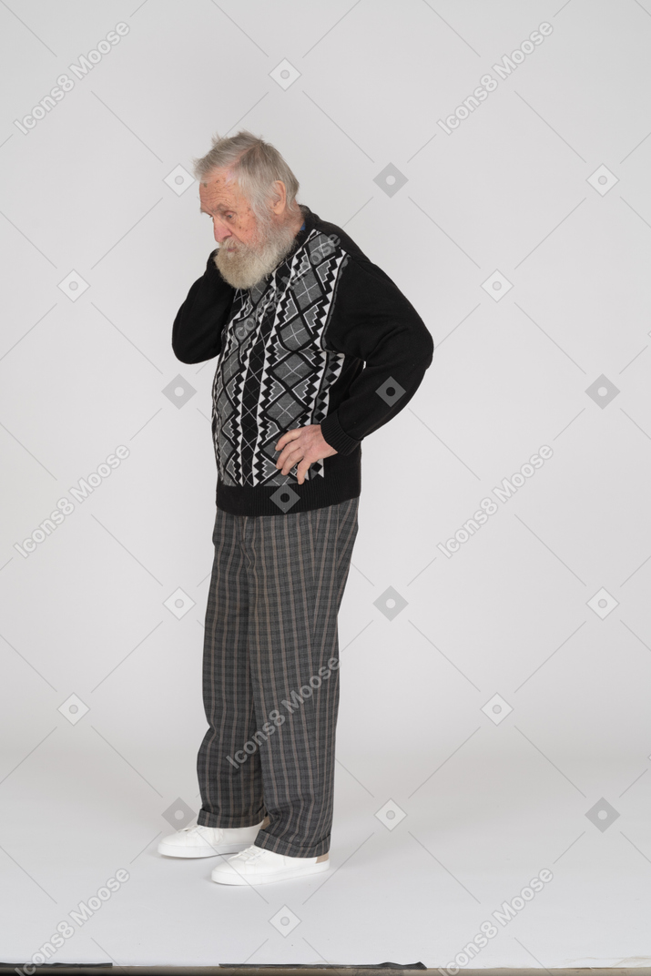 Old man standing akimbo and looking down