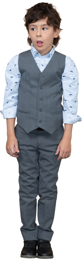 Vista frontal de un niño impresionado en traje mirando a un lado