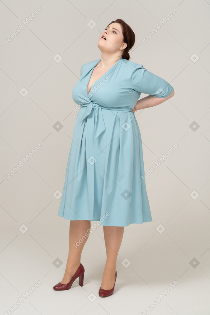 Front view of a woman in blue dress suffering from pain in lower back