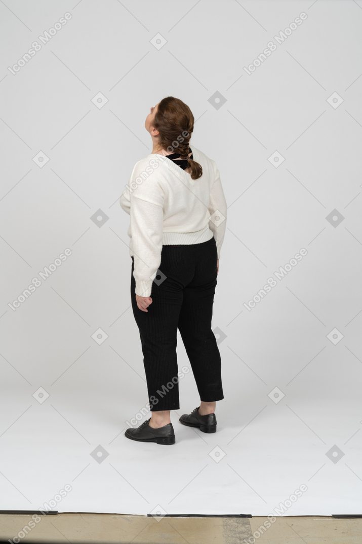 Vista trasera de una mujer regordeta en ropa casual mirando hacia arriba