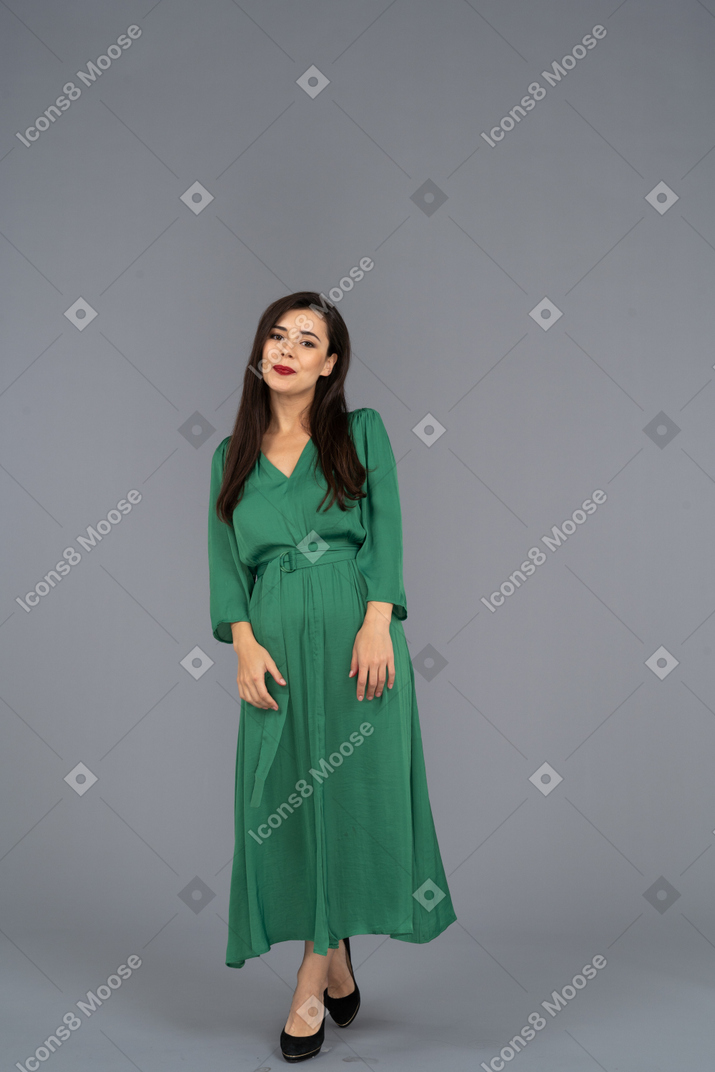 Front view of a shy smiling young lady in green dress