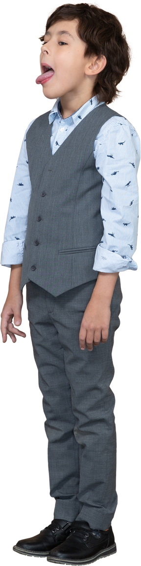 Side view of a cute boy in grey suit showing tongue