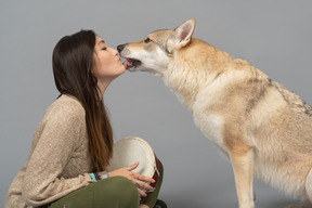 Красивая породистая собака целует молодую женщину