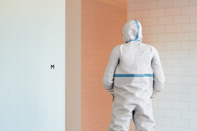 A person in a white protective suit standing next to a wall