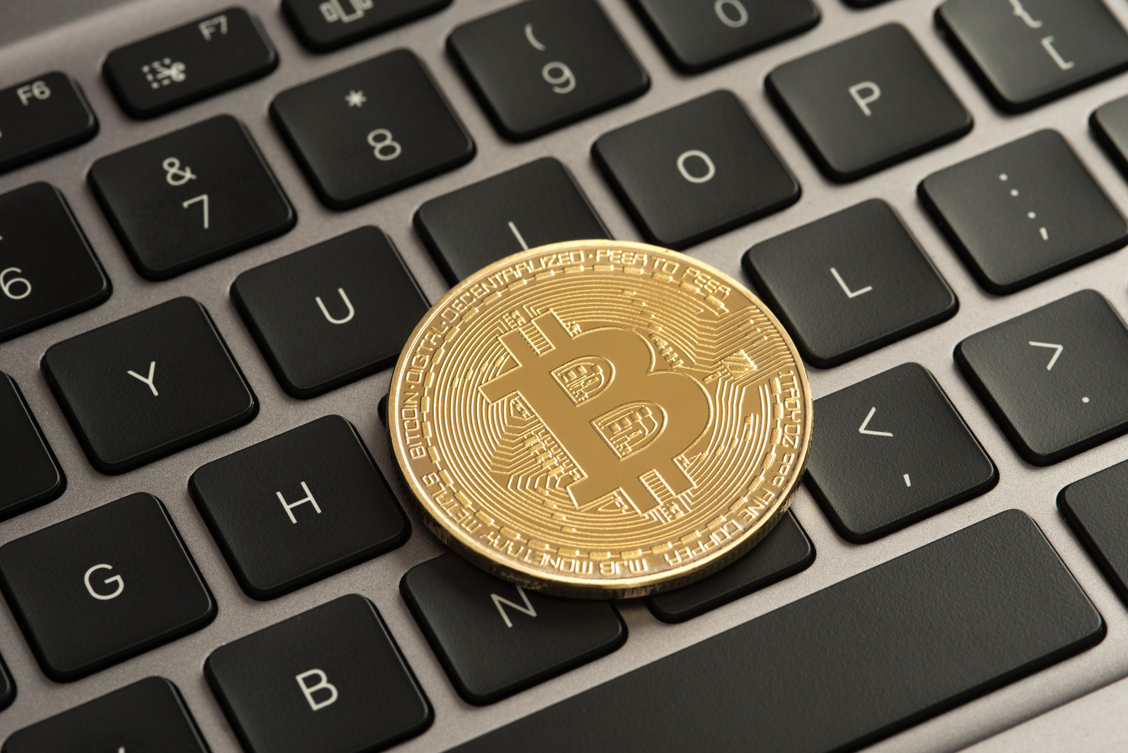 Golden bitcoin on black keyboard
