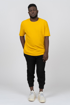 静止している黄色のtシャツを着た若い浅黒い肌の男の正面図