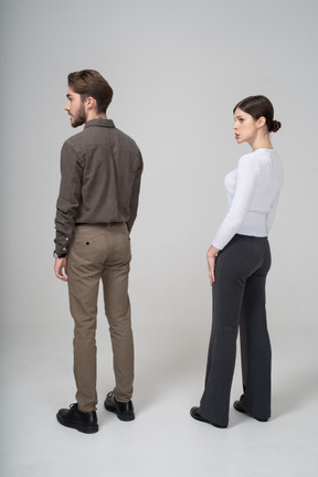 Vista posteriore di tre quarti di una giovane coppia smorfie in abiti da ufficio