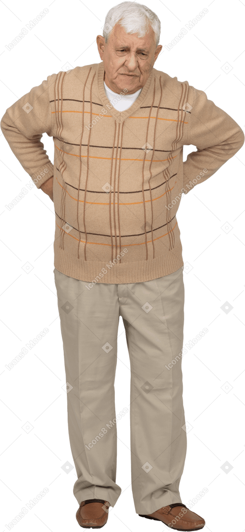 Front view of an old man in casual clothes suffering from back pain