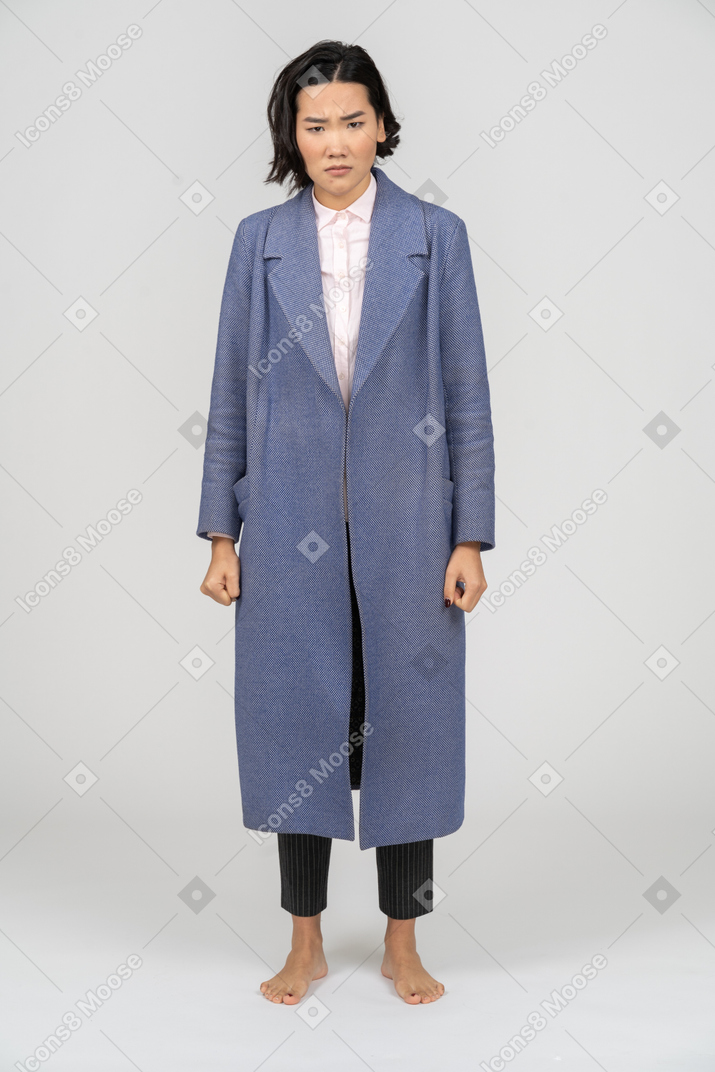 Sad woman in coat standing with arms at sides