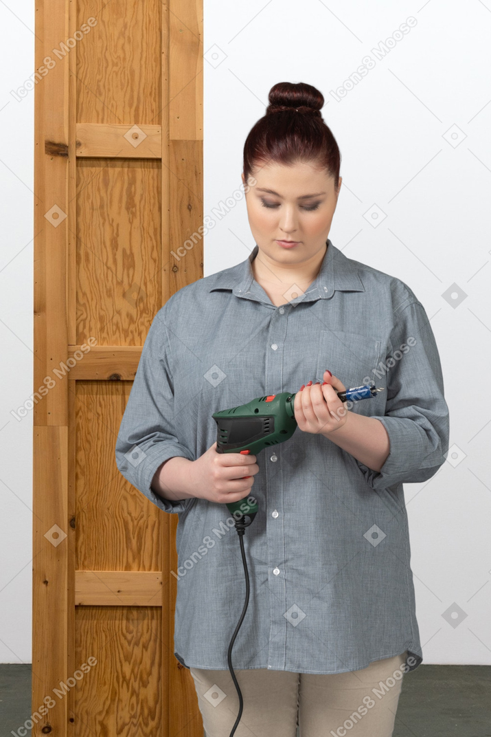 A woman in a blue shirt is holding a drill