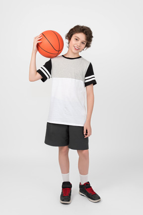 Boy holding basketball ball on his shoulder