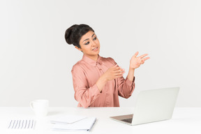 Junge indische frau, die am schreibtisch sitzt und mit einer hand zeigt