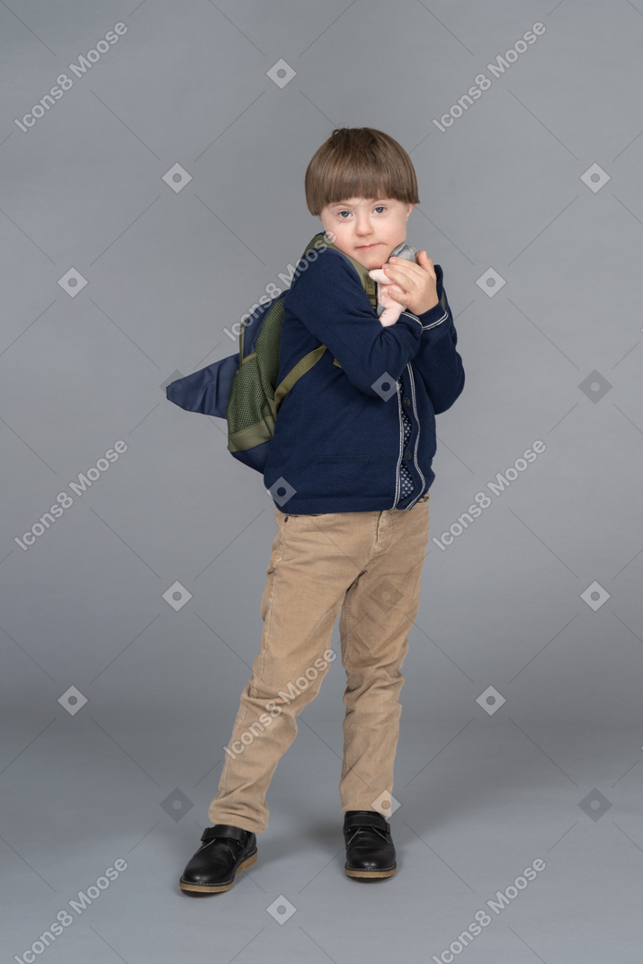 Little boy with a backpack hugging a plushie