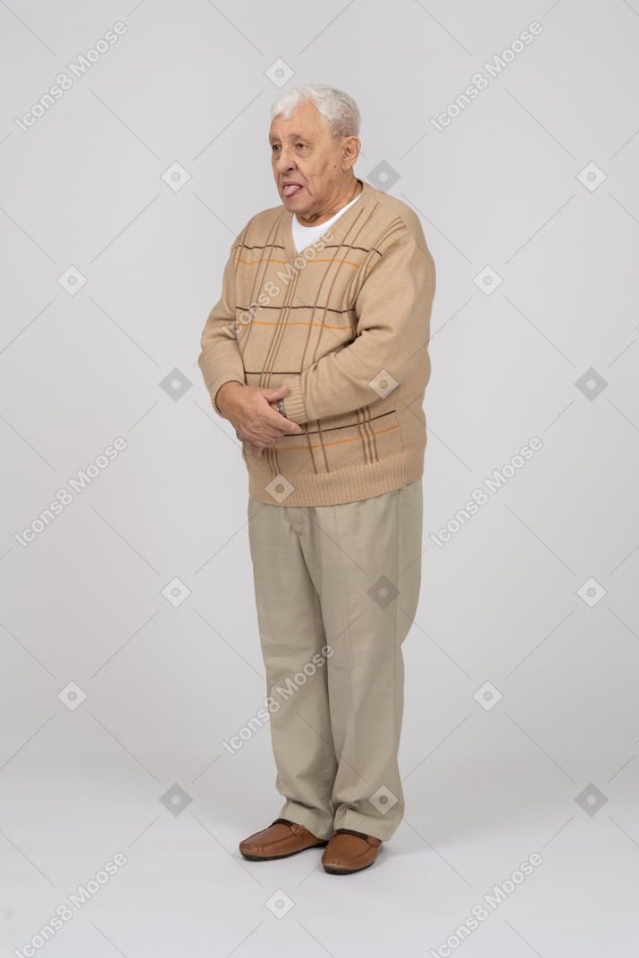 Front view of an old man in casual clothes showing tongue