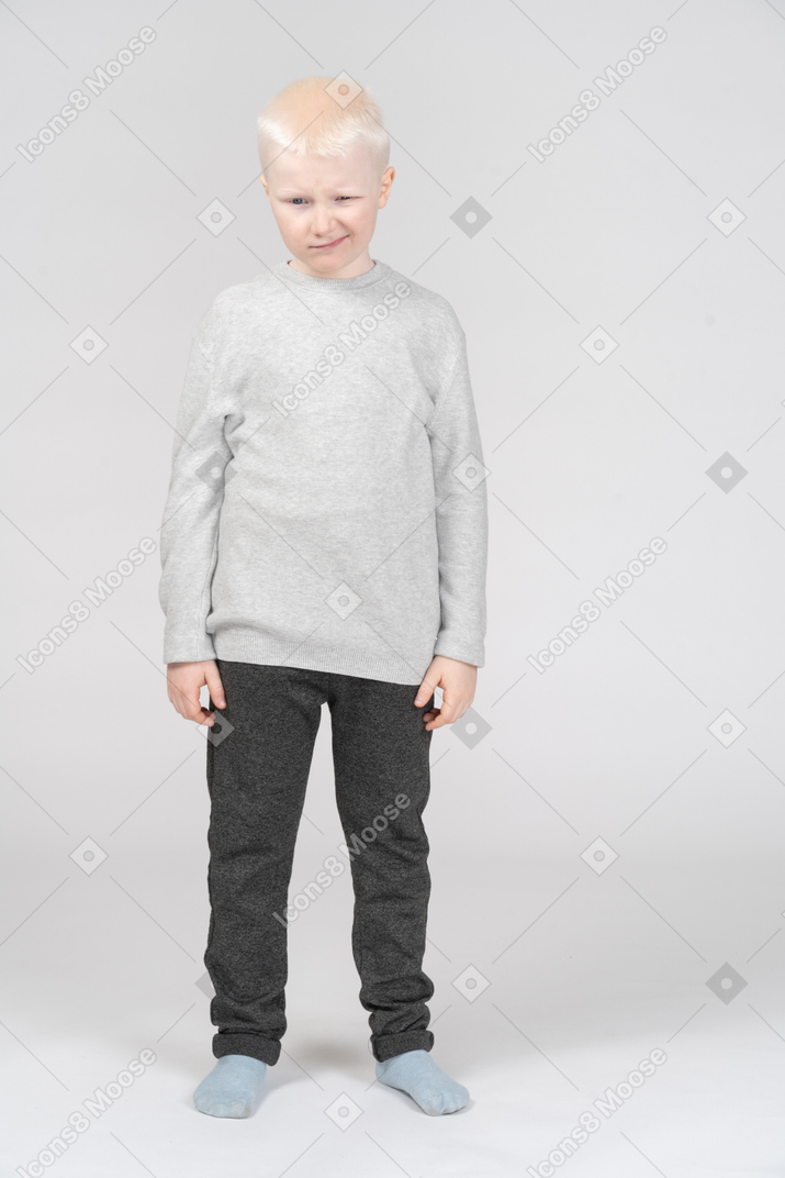 Vista frontal de um menino loiro piscando em roupas casuais