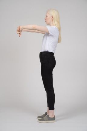 Vista lateral de uma jovem mostrando dois polegares para baixo