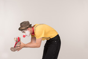 Bend male clown holding teddy bear