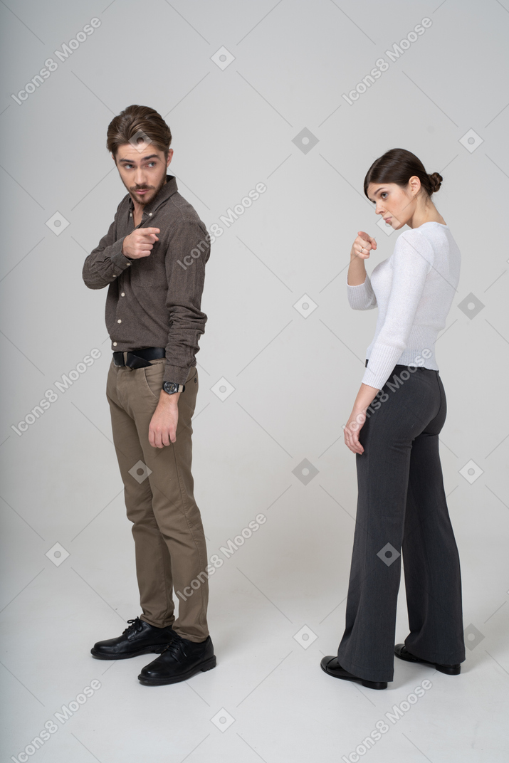 Молодая пара в офисной одежде в полный рост, указывая в сторону