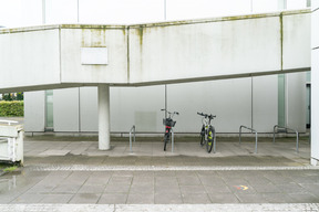 Deux vélos sur le parking devant le bâtiment blanc